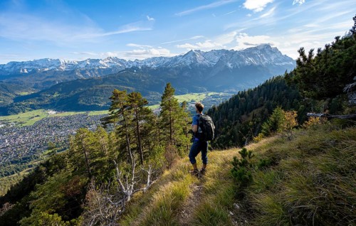 View of mountain panorama with Wetterstein mountains, mountaineer on hiking trail to Kramerspitz,