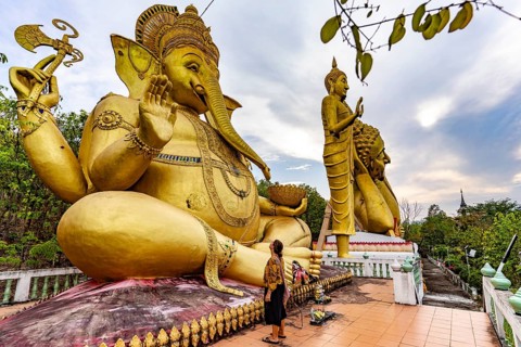 Tourist in front of the huge golden Ganesha statue of the Buddhist temple Wat Mokkanlan in Chom