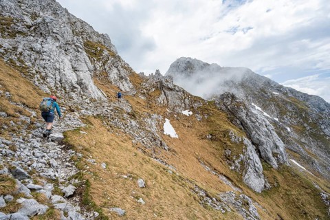 Mountaineer on a narrow hiking trail, ascent to the Maukspitze, clouds moving around the mountains,