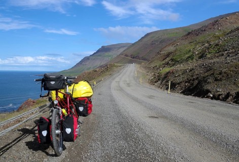 Lonely bike with panniers on a gravel road along the coast with sea and mountains, cycle tour,