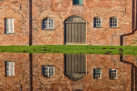 Window and Tor tor of the historic salt storehouse, symmetrical reflection on the water surface of