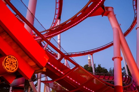 Red-lit roller coaster at dusk, Tivoli Amusement and Recreation Park, Copenhagen, Denmark, Europe
