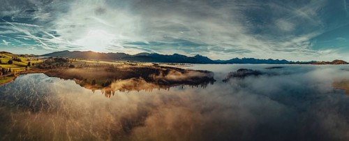 Autumn sunrise in the foothills of the Alps with fog at Illasbergsee and Forggensee near Halblech