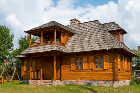 Traditional, light brown wooden house with veranda surrounded by sunshine, Bialowieza, Bialowieza,