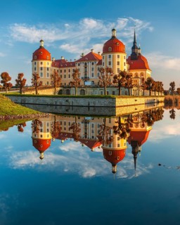 Moritzburg Castle in autumn under a blue sky, reflection in the castle pond, hunting lodge of
