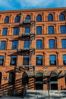 Facade of a brick building with rows of windows and shadows from a staircase, Manufaktura, Lódz,