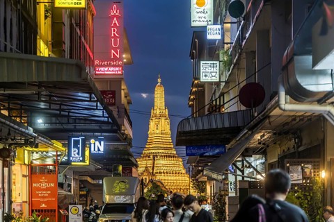 Wat Arun, Temple of Dawn at sunset with dark clouds. Boats on the Chao Phraya river. Tourist