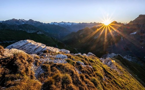 Mountain landscape at sunrise with sun star, view of mountain peaks of the Venediger group and into