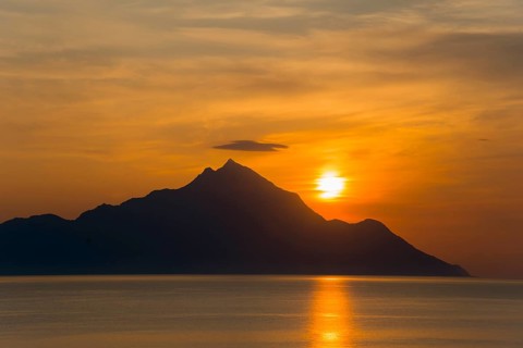 Sunrise behind a mountain with golden reflections on the sea, view of Mount Athos, Orthodox