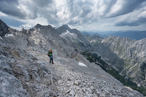 Mountaineer with helmet on a narrow rocky path, crossing the Jubiläumsgrat, view of Zugspitze and
