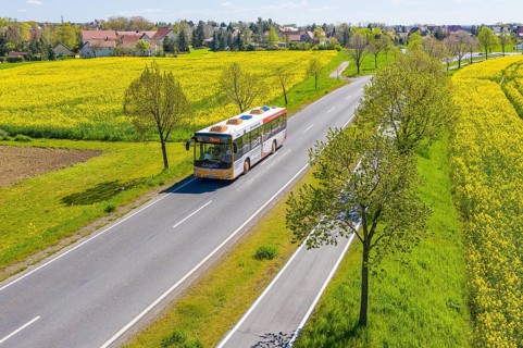 Aerial view of a bus on a country road between blossoming rape fields, Verkehrsgesellschaft Meißen