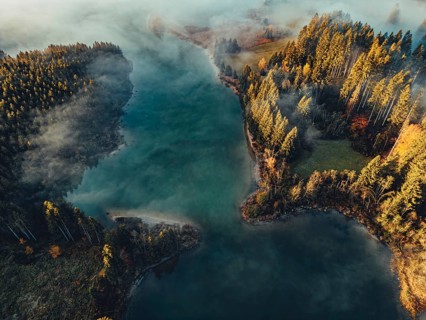 Autumn sunrise in the foothills of the Alps with fog at Illasbergsee and Forggensee near Halblech