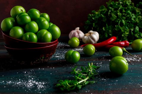 Tkemali, green cherry plum, with ingredients for sauce, cilantro, mint, hot pepper, garlic, on a