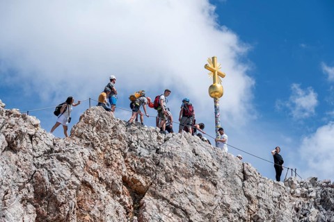 Many tourists at the summit of the Zugspitze with golden summit cross, overtourism, Wetterstein