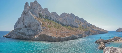 A beautiful island with a rocky coastline and a blue sea. The island is surrounded by a rocky cliff