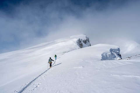 Two ski tourers in a snowy mountain landscape, ascent to the Wildhorn, cloudy mood, high tour,