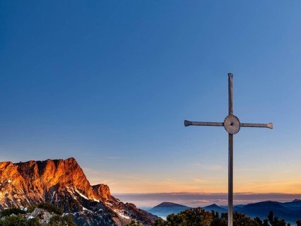 Sunrise at the summit cross of the Rauhen Kopf, behind the Untersberg, Berchtesgaden Alps,