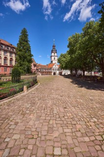 Church tower, Erbach town church, trees, cobblestone square, blue sky with cumulus clouds, market