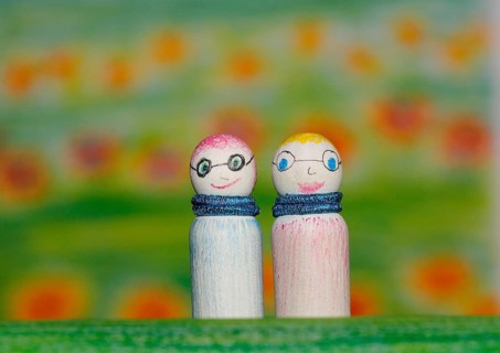 Two small funny wooden cones in front of a painted background, North Rhine-Westphalia, Germany,