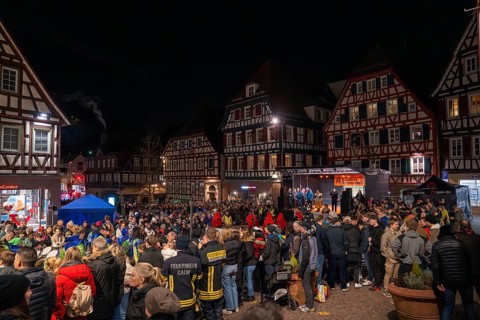 Large crowd gathers at night for a celebration in front of half-timbered houses, carnival, Calw,