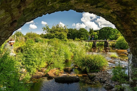 Tourists on the medieval stone slab bridge Clapper Bridge in Postbridge, Dartmoor, Devon, England,