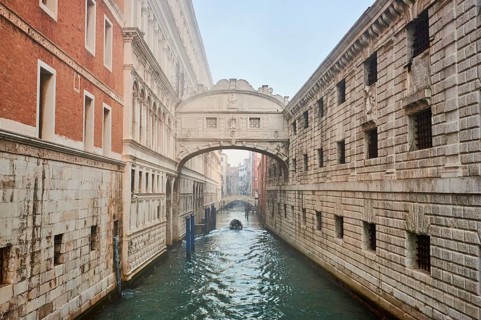 View from 'Ponte della paglia' on the bridge 'Bridge of Sighs' over a waterway before sunrise in