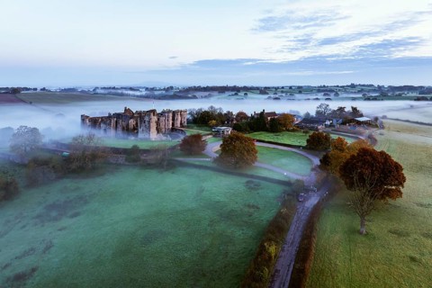 Raglan Castle in the fog at dawn from a drone, Monmouthshire, Wales, England, United Kingdom,
