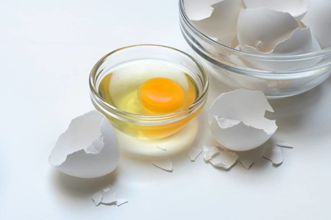 Egg whites and egg yolks in glass bowl and egg shells, whisk
