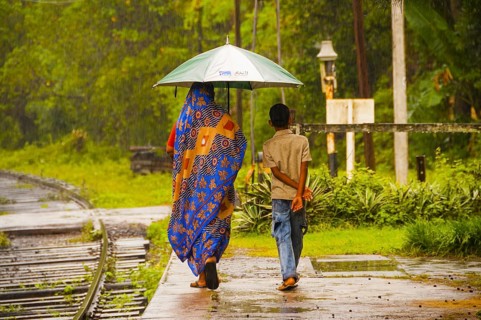 Sinhalese, mother and son, with umbrella in heavy rain, monsoon, railway station in Kalawewa, Sri
