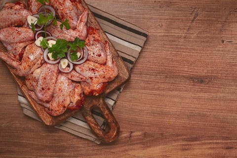 Chicken wings, marinated and laid out on a wooden platter, ready for cooking, grilling or baking,