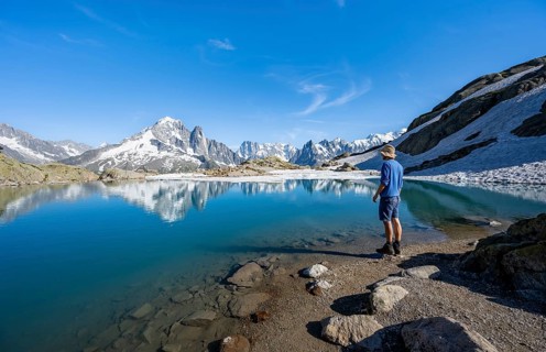 Mountaineer in front of mountain landscape with mountain lake, tourist at Lac Blanc with water
