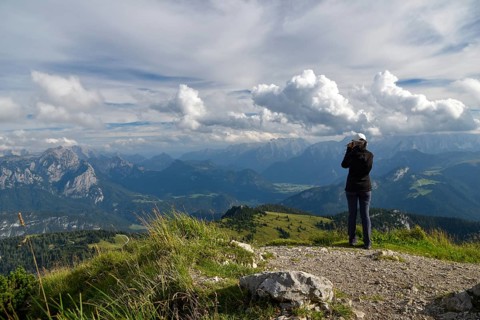 Hiker enjoying the view from the summit of the Sonntagshorn to the horse-rider Alm and Loferer