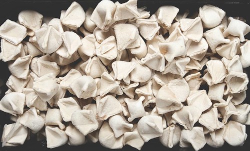 Traditional Turkish dumplings, raw, in a black container, top view, no people