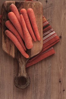 Fresh carrots on a chopping board, wooden table, raw carrots, no people