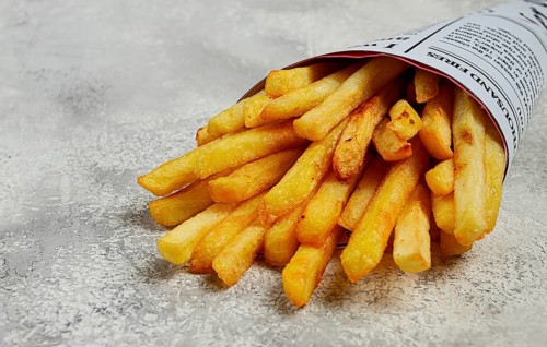 Fried French fries in a paper bag, on an abstract background, without people, in a rustic style, in