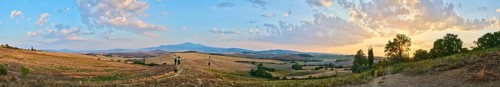 Typical Tuscan landscape in Val d'Orcia with hills, trees, fields, cypresses and farm road in