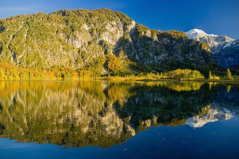 Lake Almsee in autumn with mountains reflected in the lake. Blue sky with no clouds