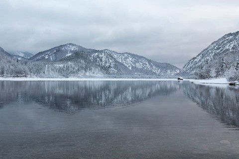 Snow covered boat shelter on Lake Almsee which is partly frozen and snow covered. Snow on the