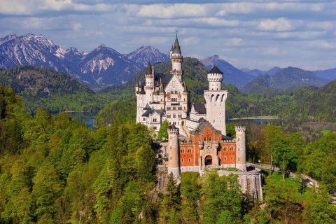 Neuschwanstein Castle with majestic Alpine peaks in the background, shrouded in clouds, Schwangau,