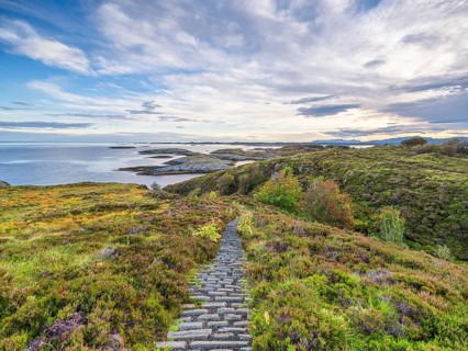 Hiking trail with a view of the sea along the Atlantic Road, blue sky with clouds,
