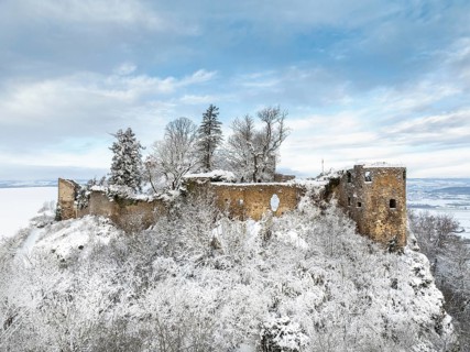 Aerial view of the snow-covered Hegau volcano Mägdeberg with remains of a castle wall on a cold
