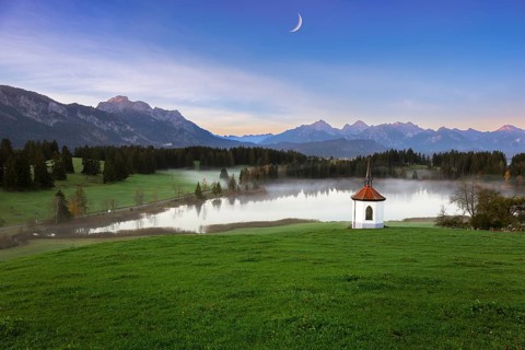 Idyllic mountain landscape with chapel and lake in the evening light, peaceful atmosphere, crescent