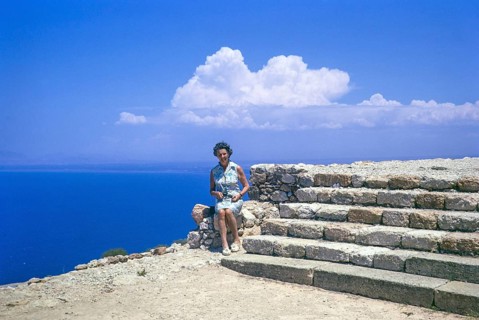 Woman tourist sitting on stone wall at Roman ruins of Vouni Palace, Lefke, Northern Cyprus, Europe