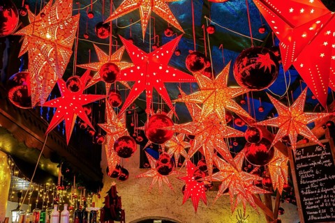 Decoration with stars and baubles above mulled wine stand in side passage at Christmas market, Bad