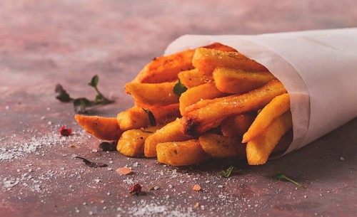 Fried French fries, in a paper bag, on an abstract background, no people, rustic
