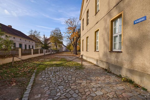 Houses with autumnal trees, square cordoned off with a rusty chain, school square, Mühlberg Elbe,