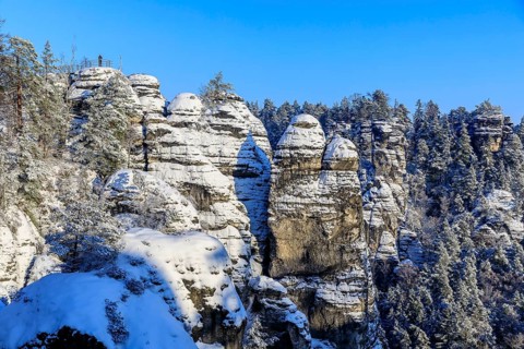 View of snow-covered rocks and trees from the Bastei bridge into the Wehlgrund, on the left in the