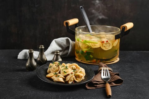 A plate of delicious dumplings is presented alongside a pot of steaming broth filled with