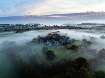 Raglan Castle in the fog at dawn from a drone, Monmouthshire, Wales, England, United Kingdom,