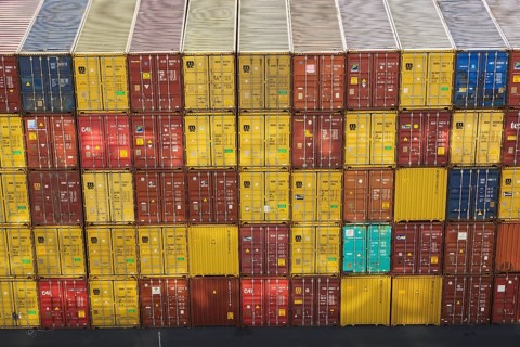 High angle view of stacked yellow and reddish brown MSC, TEX and CAI metal box shipping containers